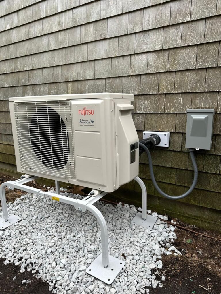 Fujitsu heat pump outdoor unit on a raised stand with gravel base